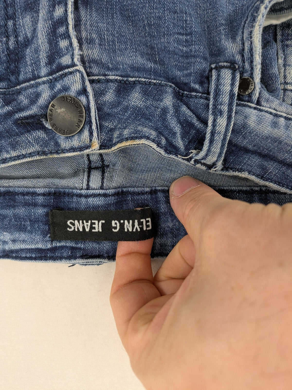FN.G blue straight jeans with AC/DC patch, smiley face, and elastic jogger cuffs.