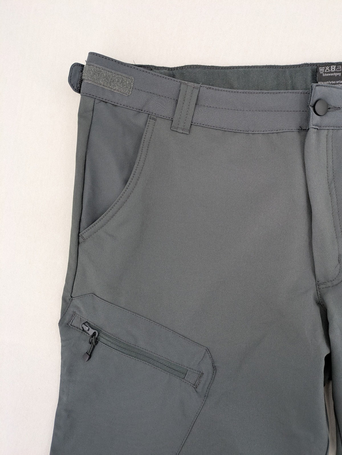 Outdoor grey functional shorts with adjustable velcro waistband and zippered leg pocket.