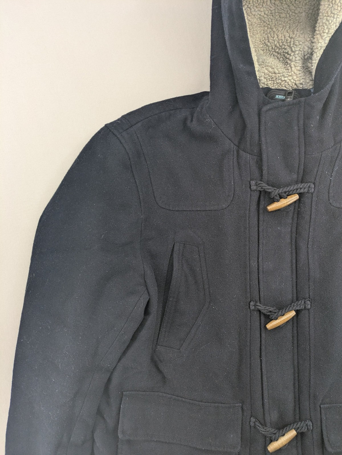 Angelo Litrico black duffle coat with toggle closure and cream Sherpa-lined hood.