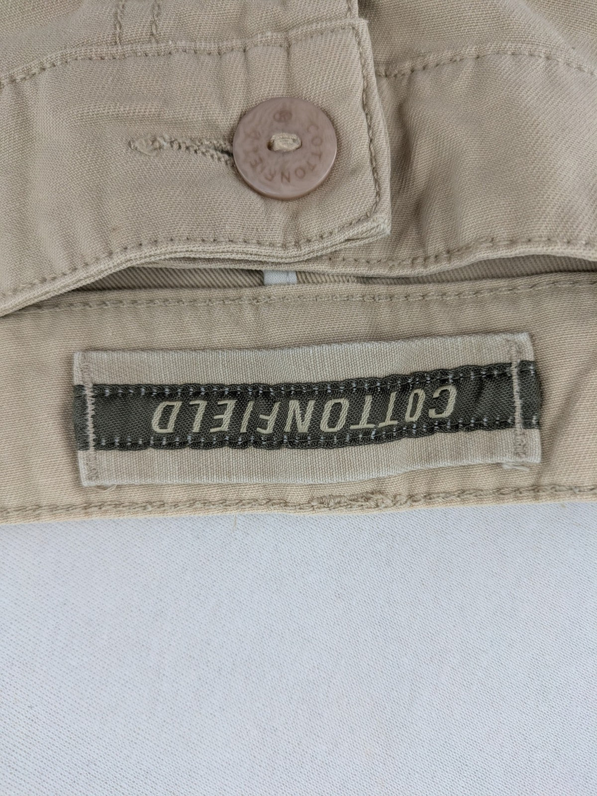 Cottonfield beige cargo pants with multiple pockets and button flaps.