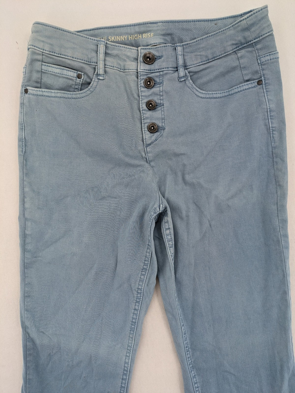 Yessica blue skinny jeans high rise with button fly and V-cut hem detail.