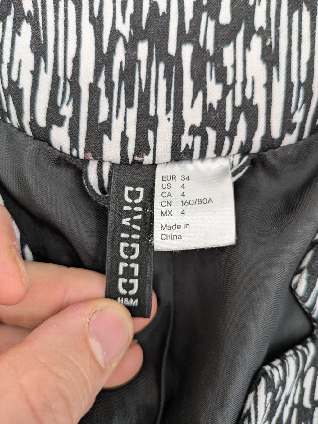 H&M Divided black and white patterned blazer with open front and two front pockets.