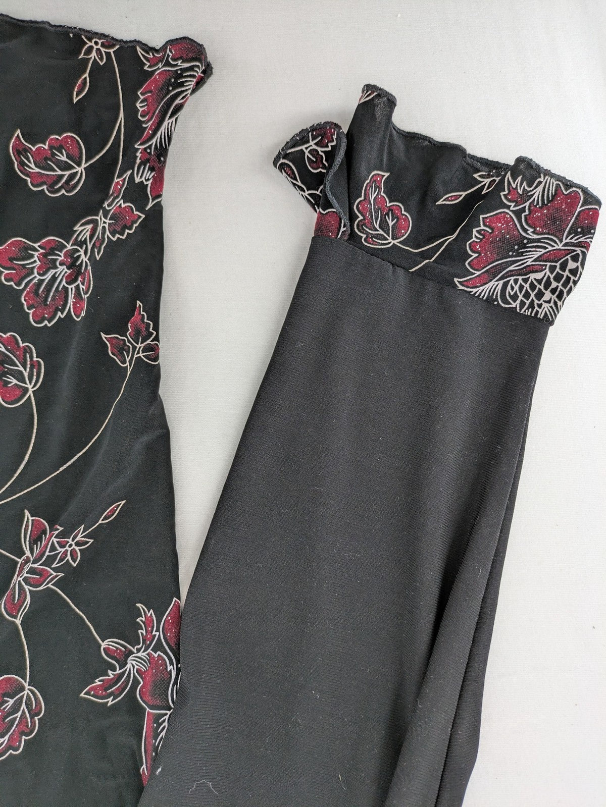 Damen black top with burgundy and white floral print, waterfall collar, and ruffled sleeves.