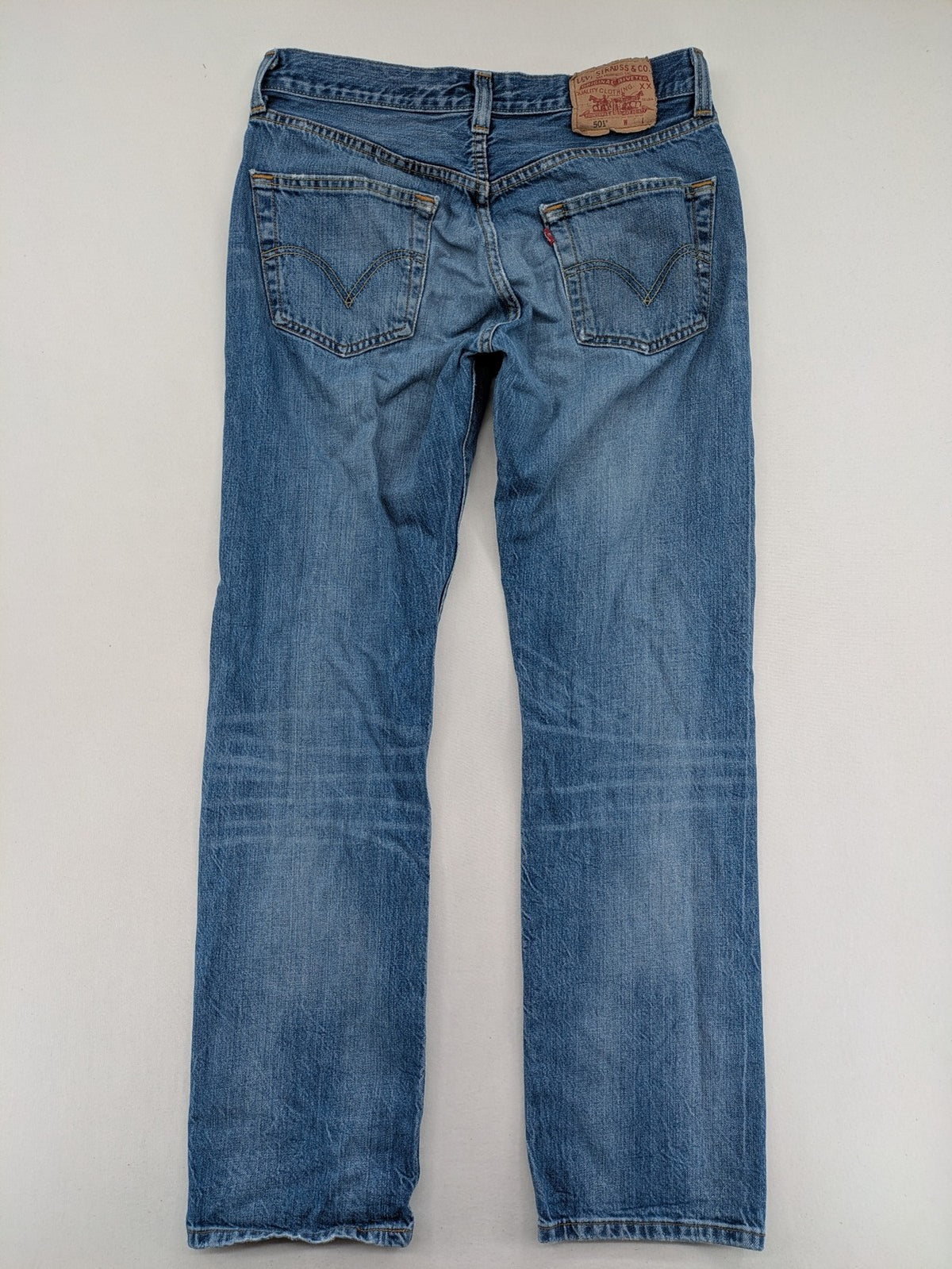 Levi's blue straight jeans with button-fly and distressed knee rips.