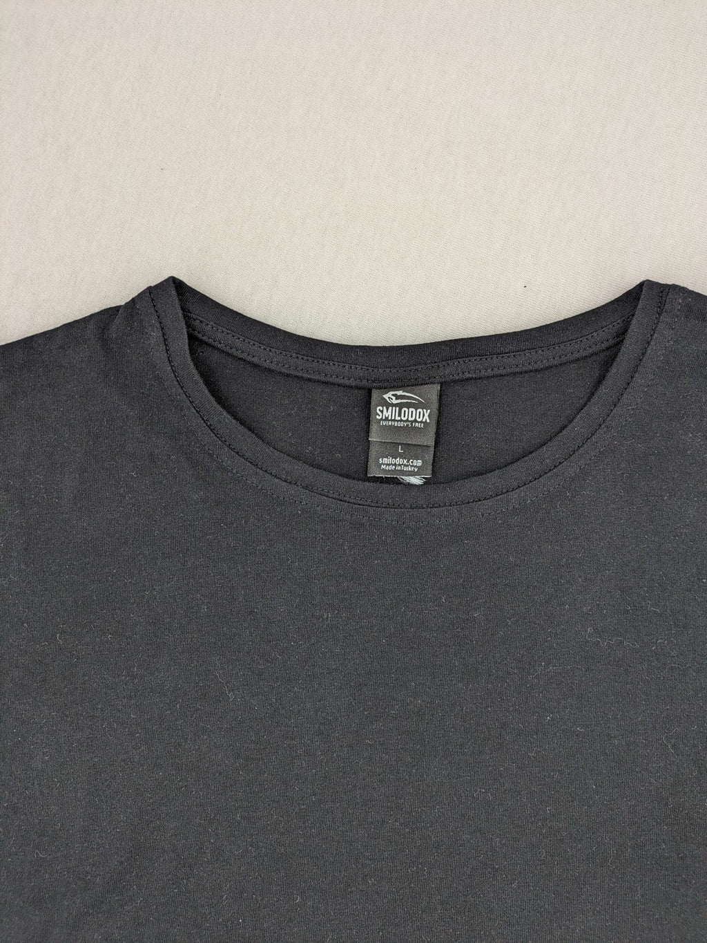 Smilodox black T-shirt minimalist design with subtle brand patch, 100% cotton.