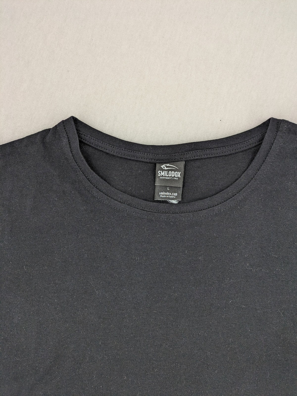 Smilodox black T-shirt minimalist design with subtle brand patch, 100% cotton.