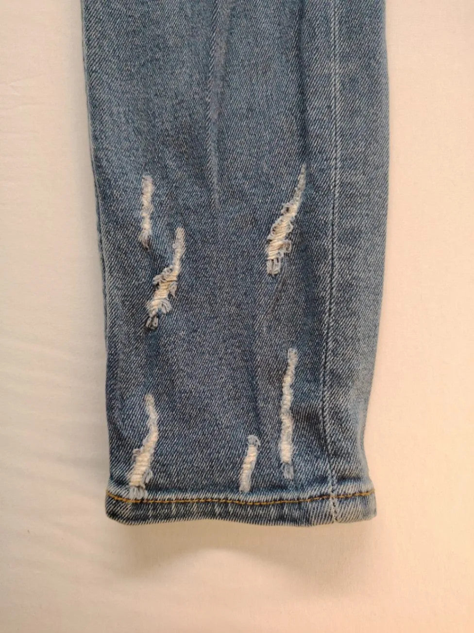 Damen blue skinny jeans with ripped details, five-pocket style, and classic button closure.