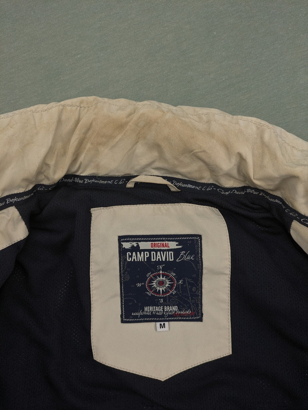Camp David beige field jacket with logo patches, standing collar, and multiple pockets.