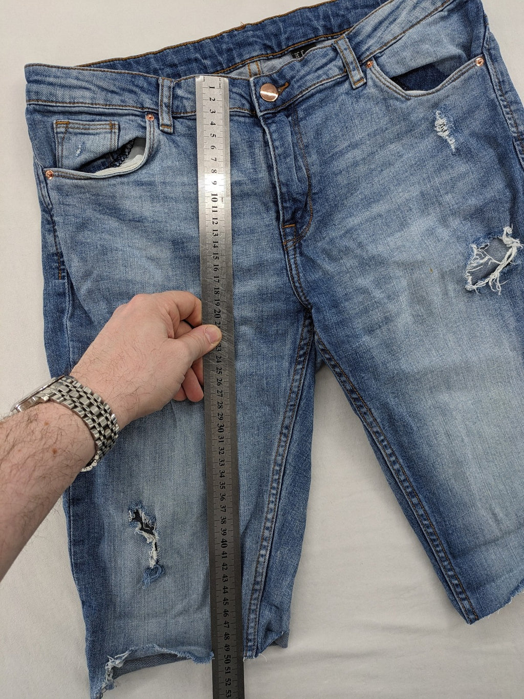 Denim blue distressed jeans shorts with frayed edges and a trendy used look.