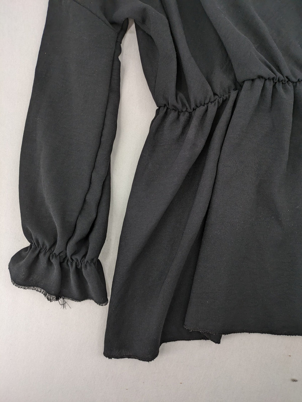 Bella black wrap blouse with deep V-neck and ruffled long sleeves.