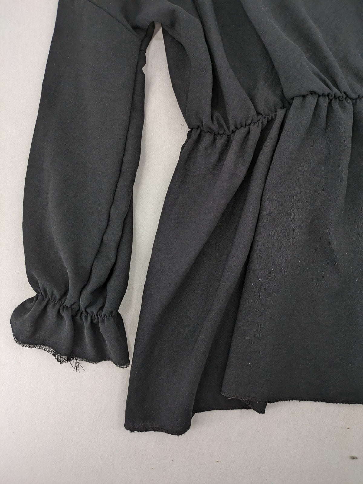 Bella black wrap blouse with deep V-neck and ruffled long sleeves.