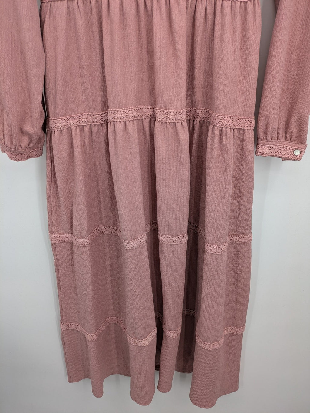 Moda pink bridal party dress with lace inserts, long sleeves, and tiered design.