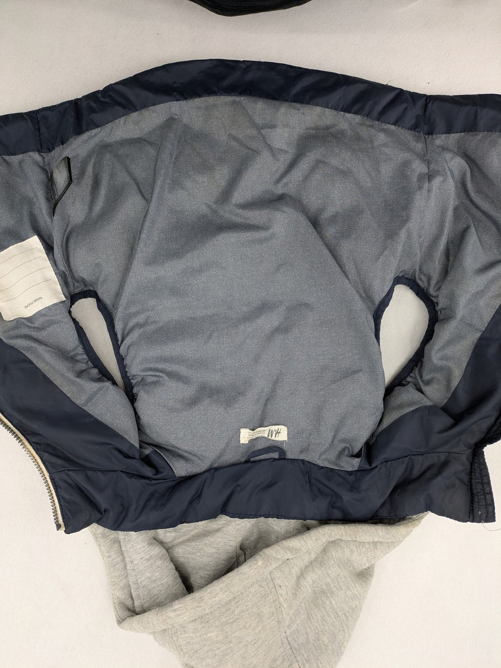 H&M navy puffer vest with grey hood and zip pockets for kids.