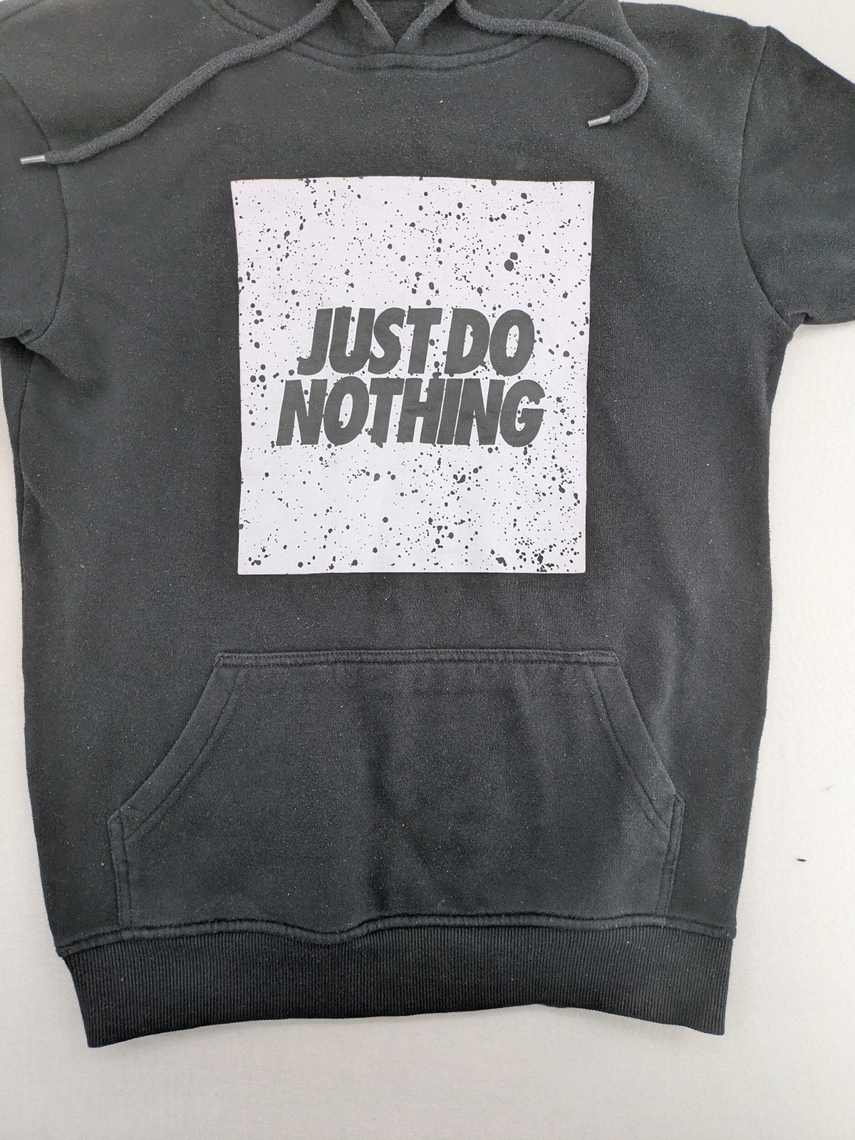 FSBN white zip-through hoodie with "Just Do Nothing" graphic and adjustable drawstring hood.