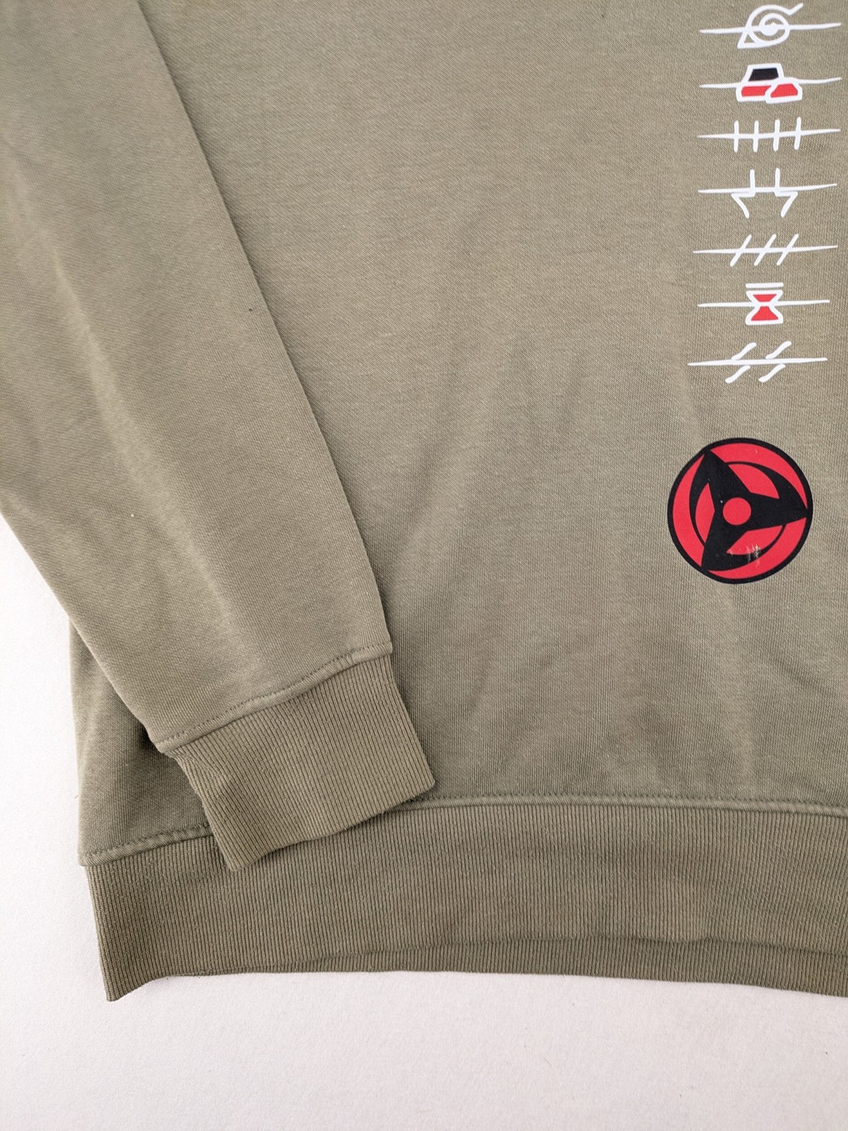 Naruto khaki turtle neck jumper featuring red Akatsuki cloud and Sharingan symbols.