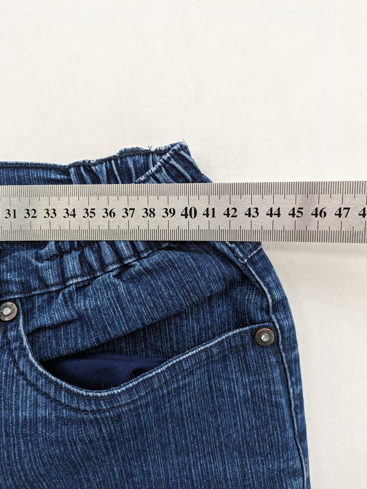 Outfit blue straight jeans with elastic waistband and embroidered crown-wing emblem on pockets.