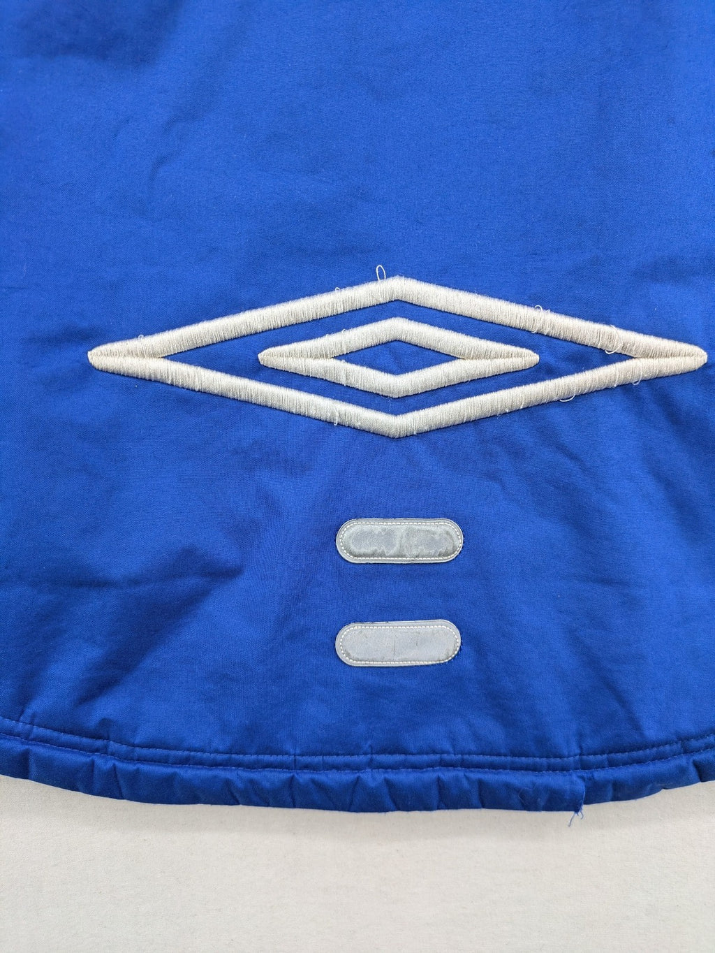 Umbro blue fleece-lined jacket with hood, reflective details, and white piping.