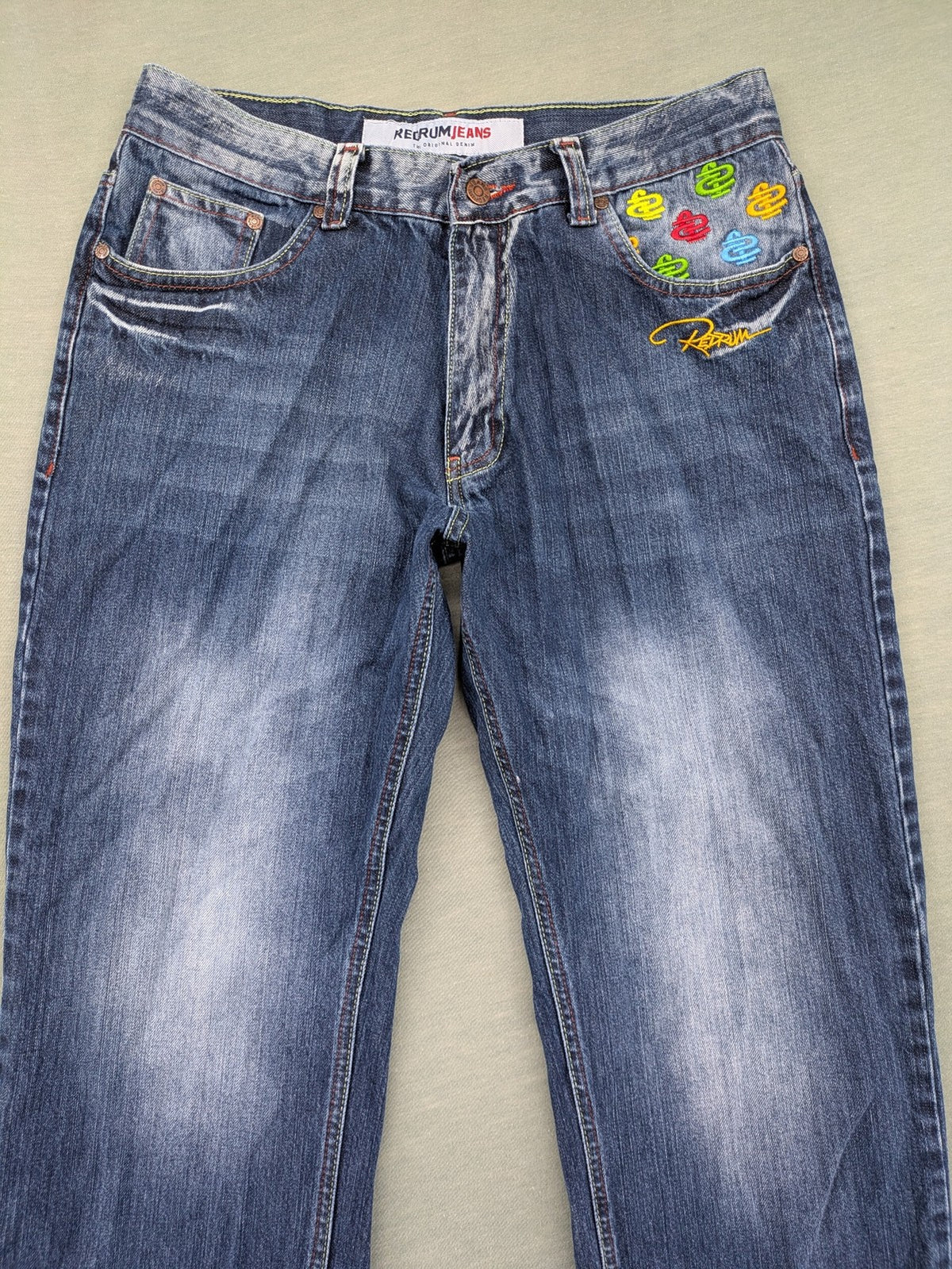 Y2K blue straight jeans with colorful logo embroidery and baggy fit.