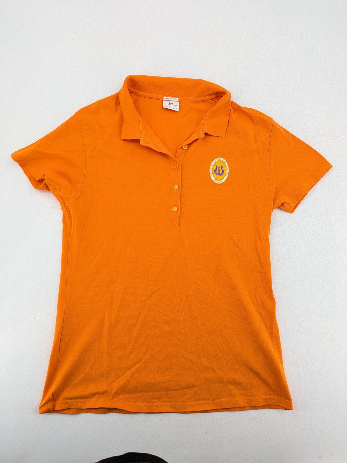 Teejays orange polo shirt with embroidered logo, classic collar, and button placket.