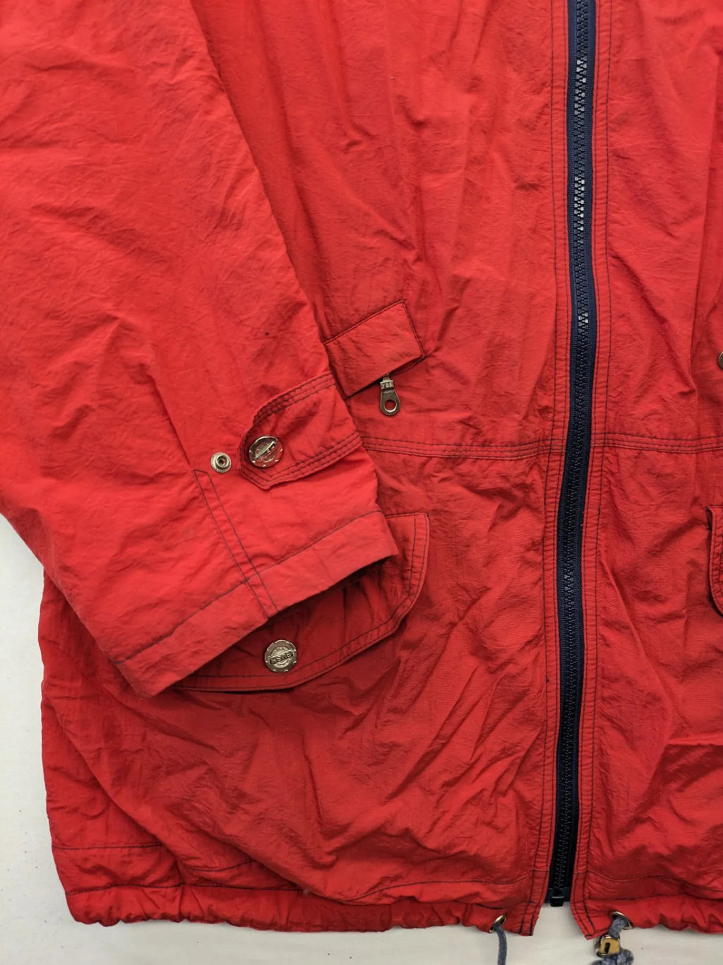 Bush Sportswear red trekking jacket with front zipper, multiple pockets, and striped lining.