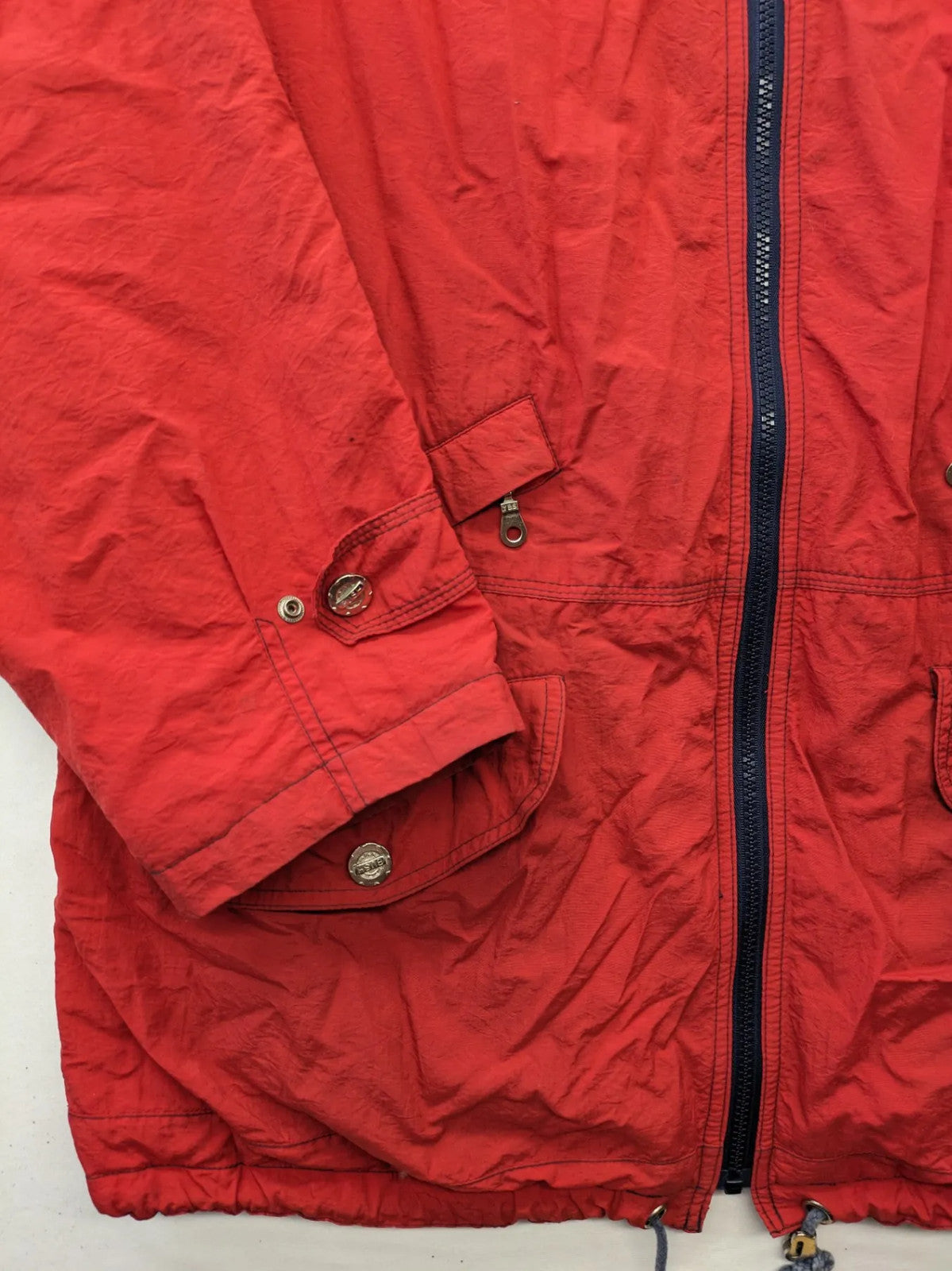 Bush Sportswear red trekking jacket with front zipper, multiple pockets, and striped lining.