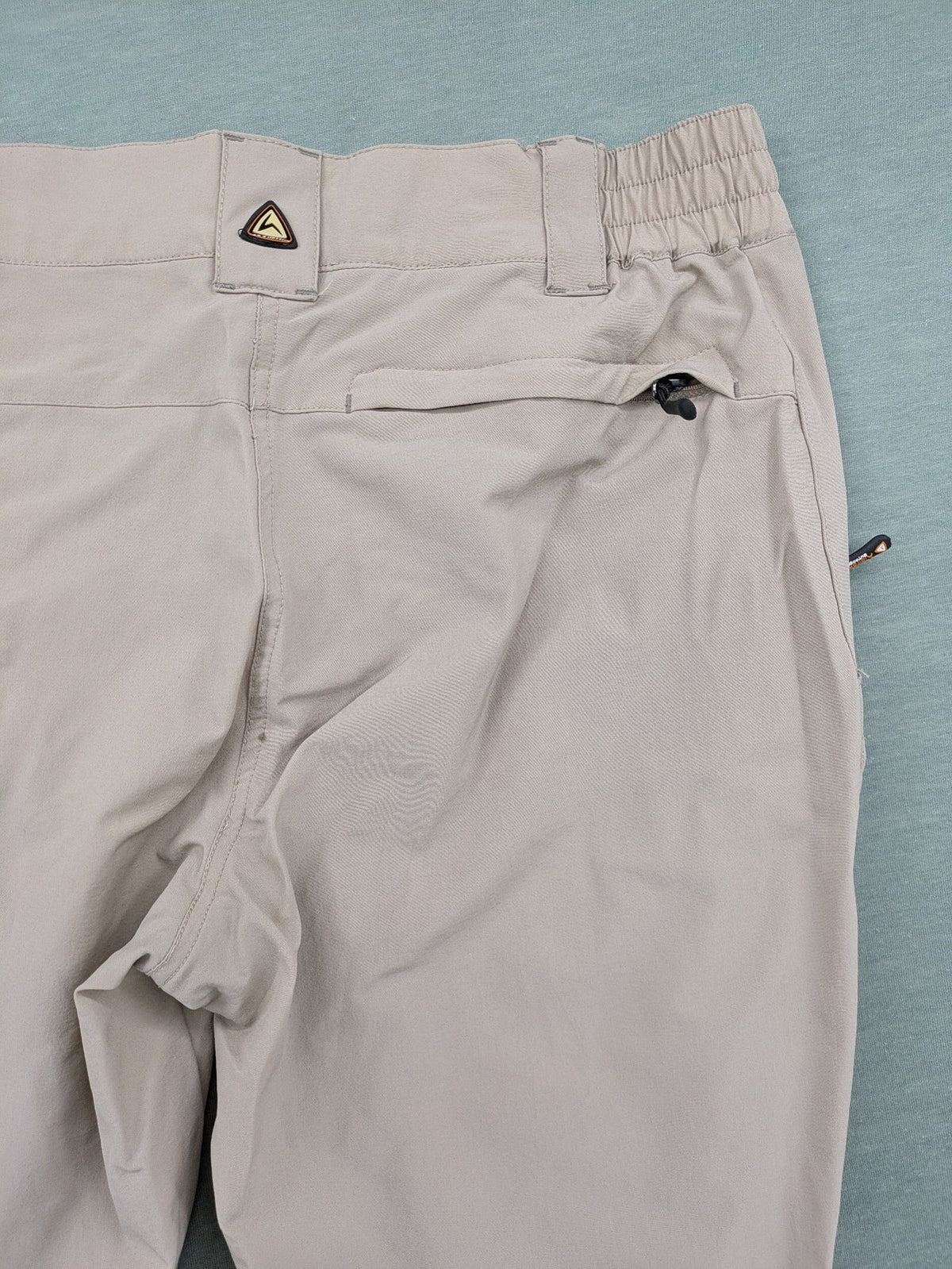 Hickory beige outdoor pants with multiple zippered pockets and stretch fabric for comfort.