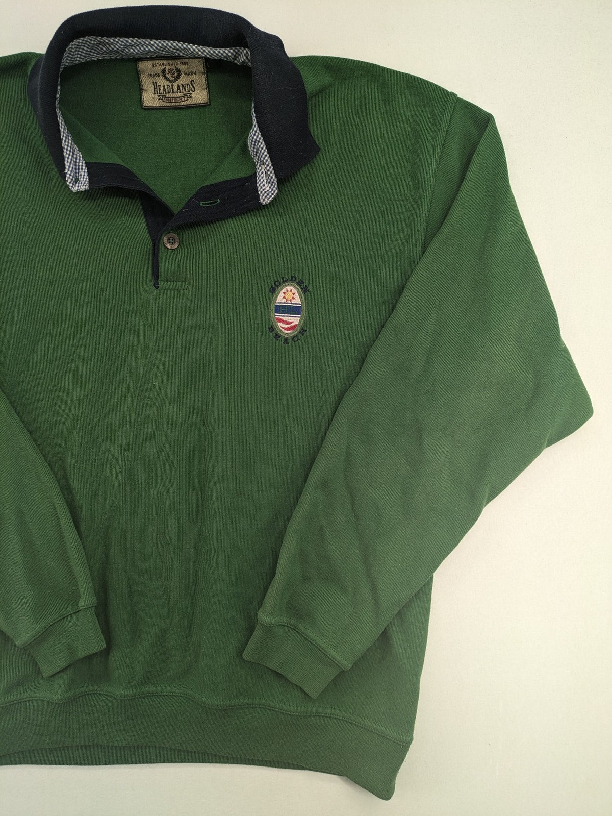 Headlands green turtle neck jumper with gingham collar and "Golden Beach" embroidery.