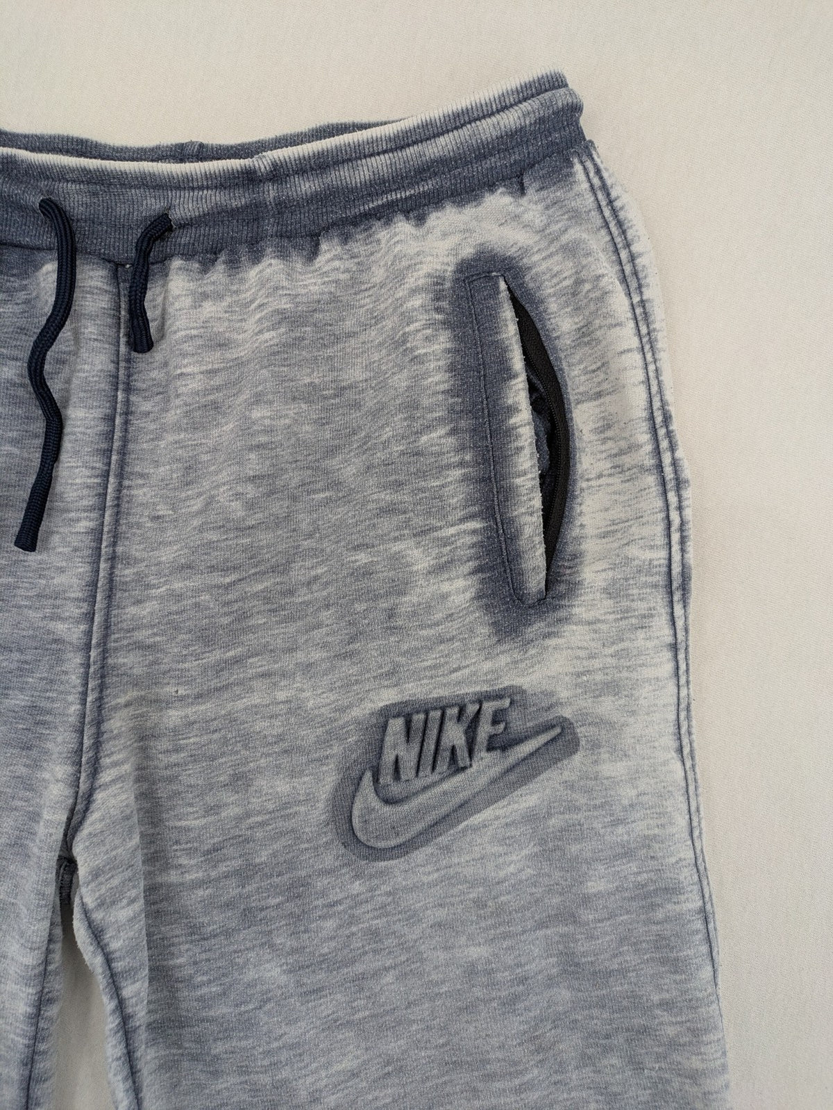 Nike grey acid wash jogger shorts with embossed logo and zip pockets.