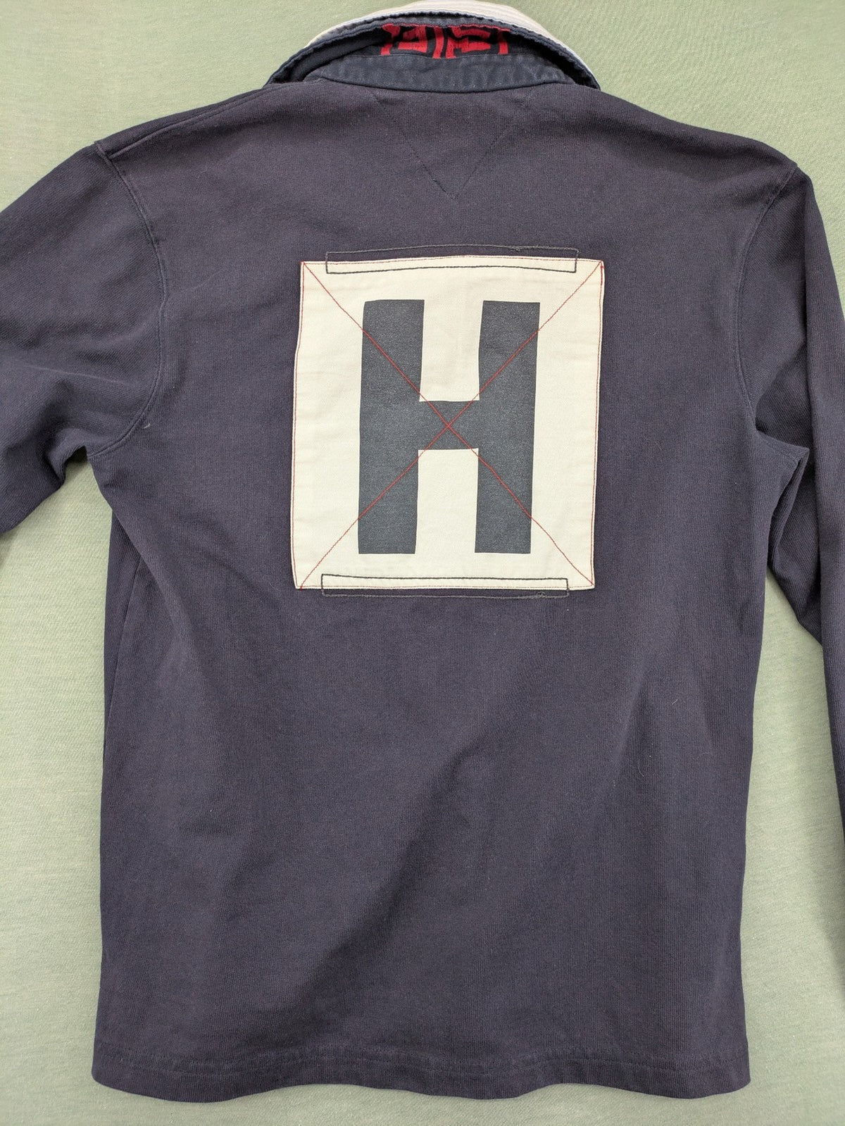 Tommy Hilfiger grey rugby polo shirt with navy striped collar and large H logo.