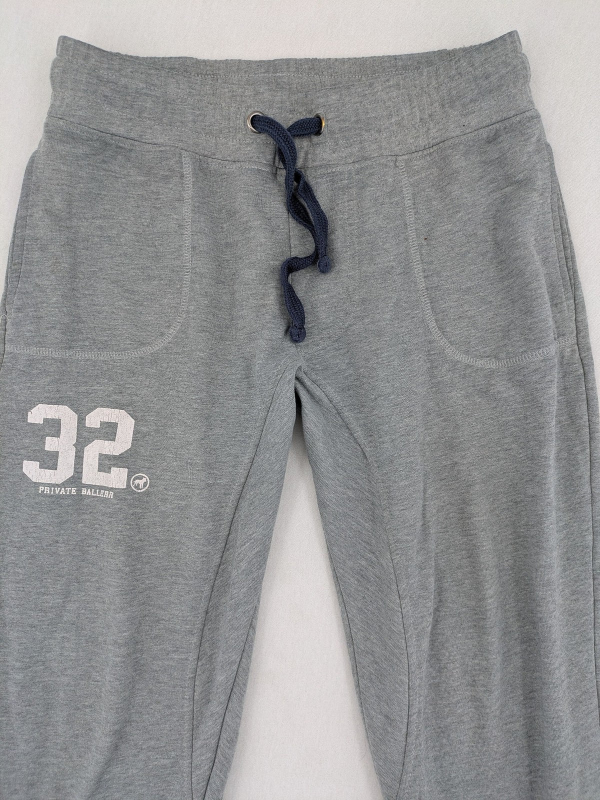Private Baller grey sweatpants with "32" graphic print and blue drawstring.