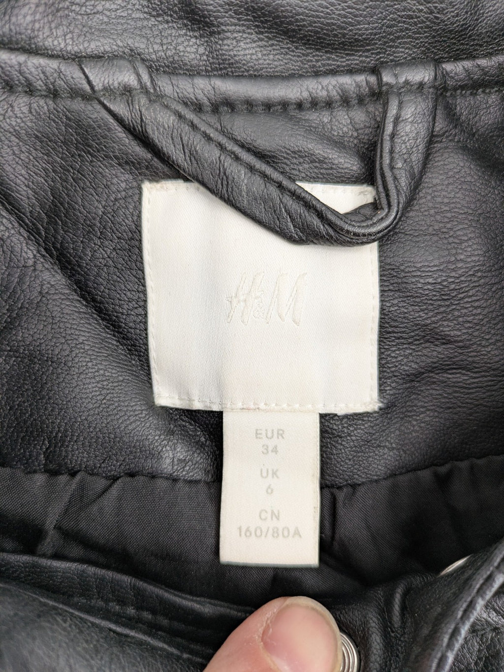 H&M black biker jacket with silver zippers, shoulder flaps, and snap-button details.