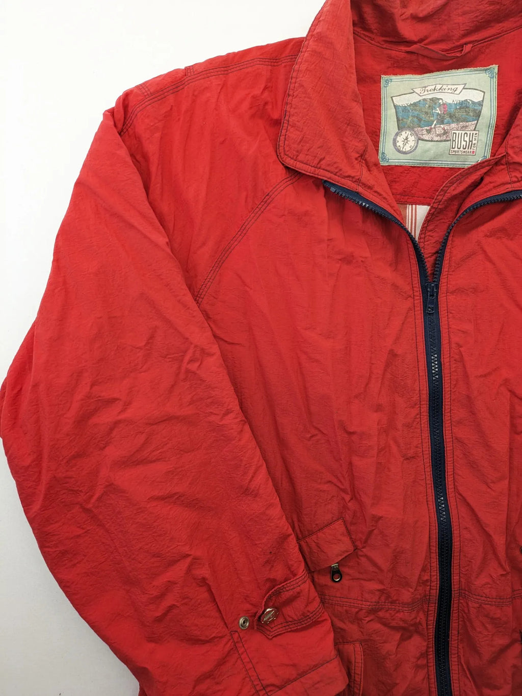 Bush Sportswear red trekking jacket with front zipper, multiple pockets, and striped lining.