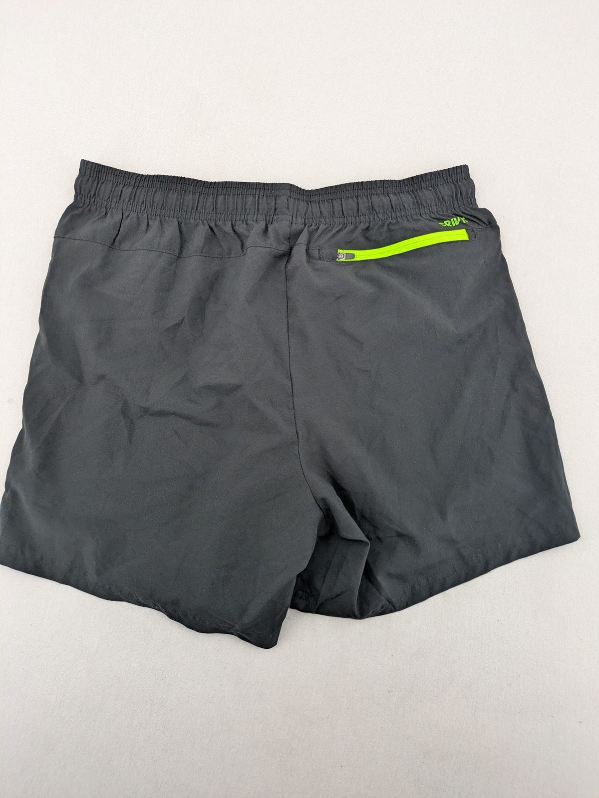 Crivit black running shorts with neon green accents, elastic waistband, and reflective details.