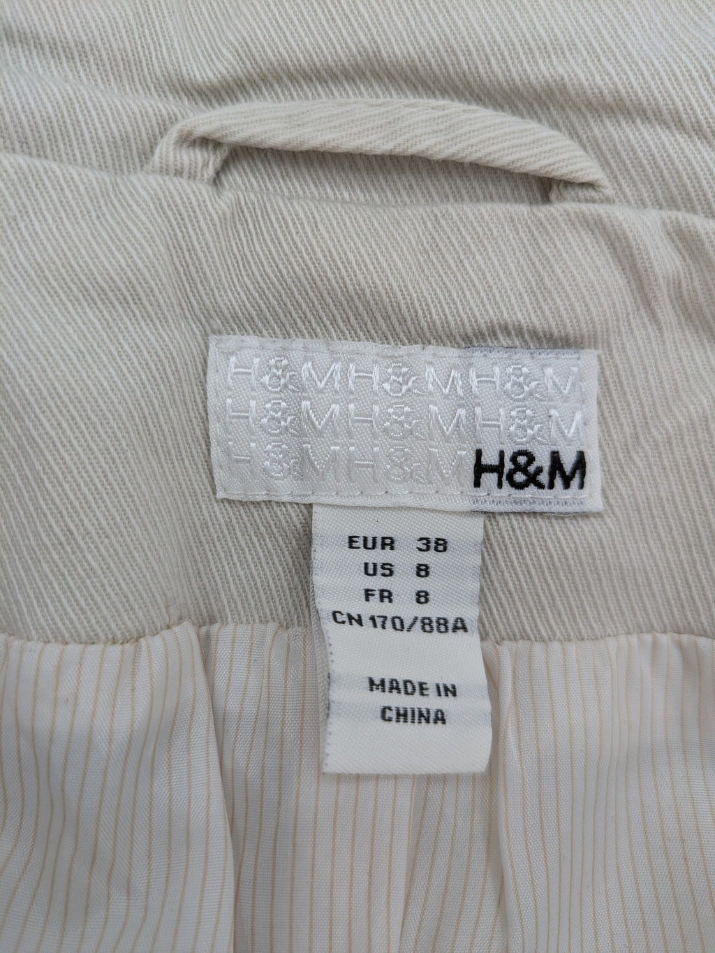 H&M beige trench coat size 38, classic design with button closure and striped lining.