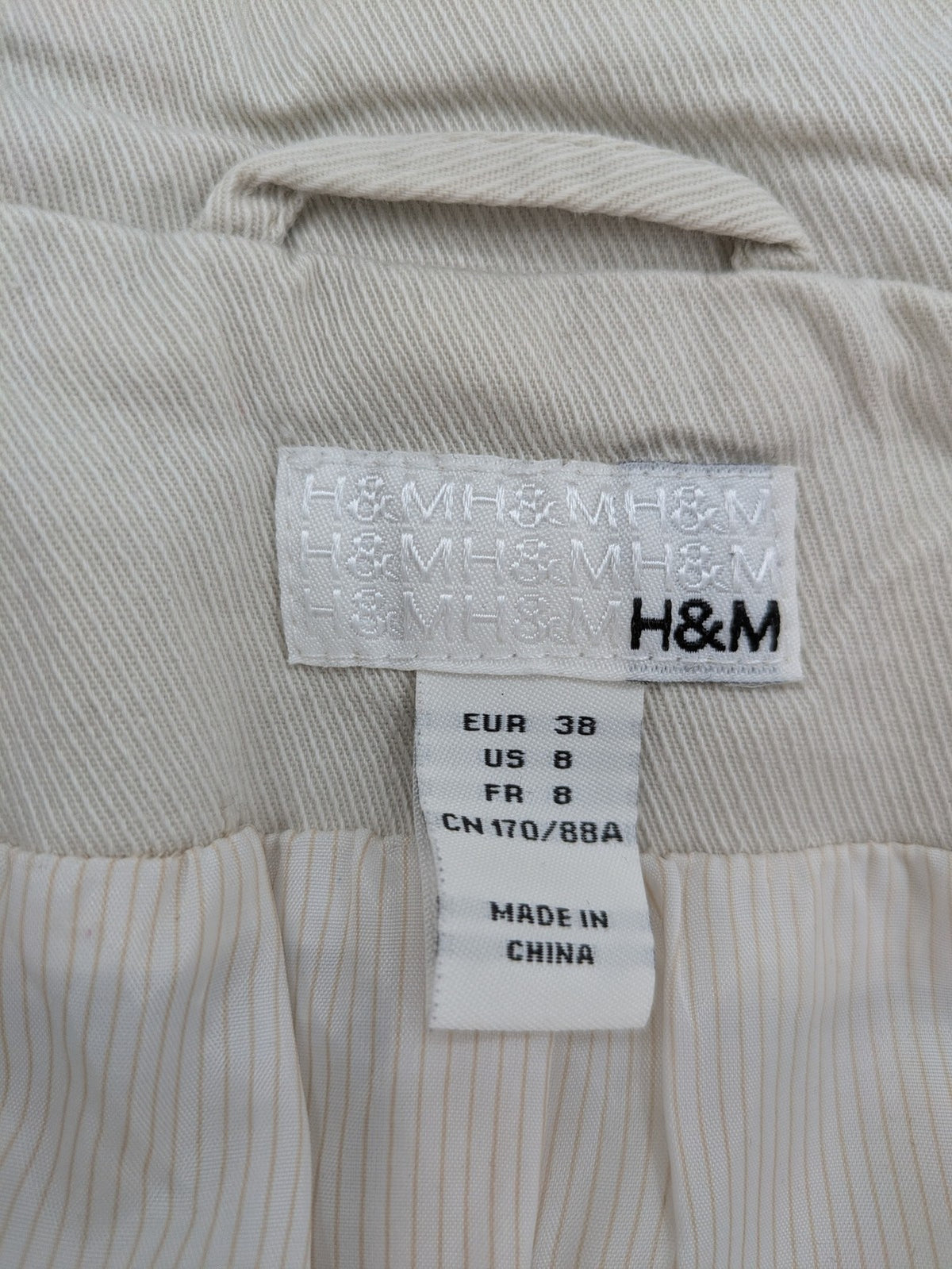 H&M beige trench coat size 38, classic design with button closure and striped lining.