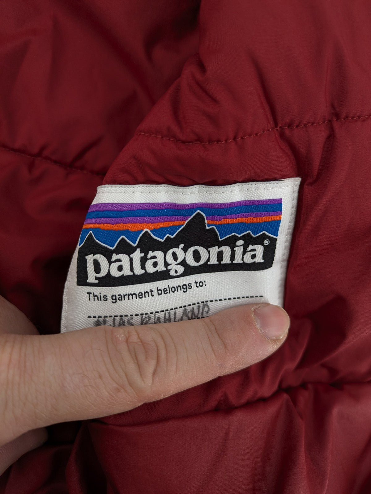 Patagonia red winter coat with hood, zip closure, snow skirt, and ski pass pocket.