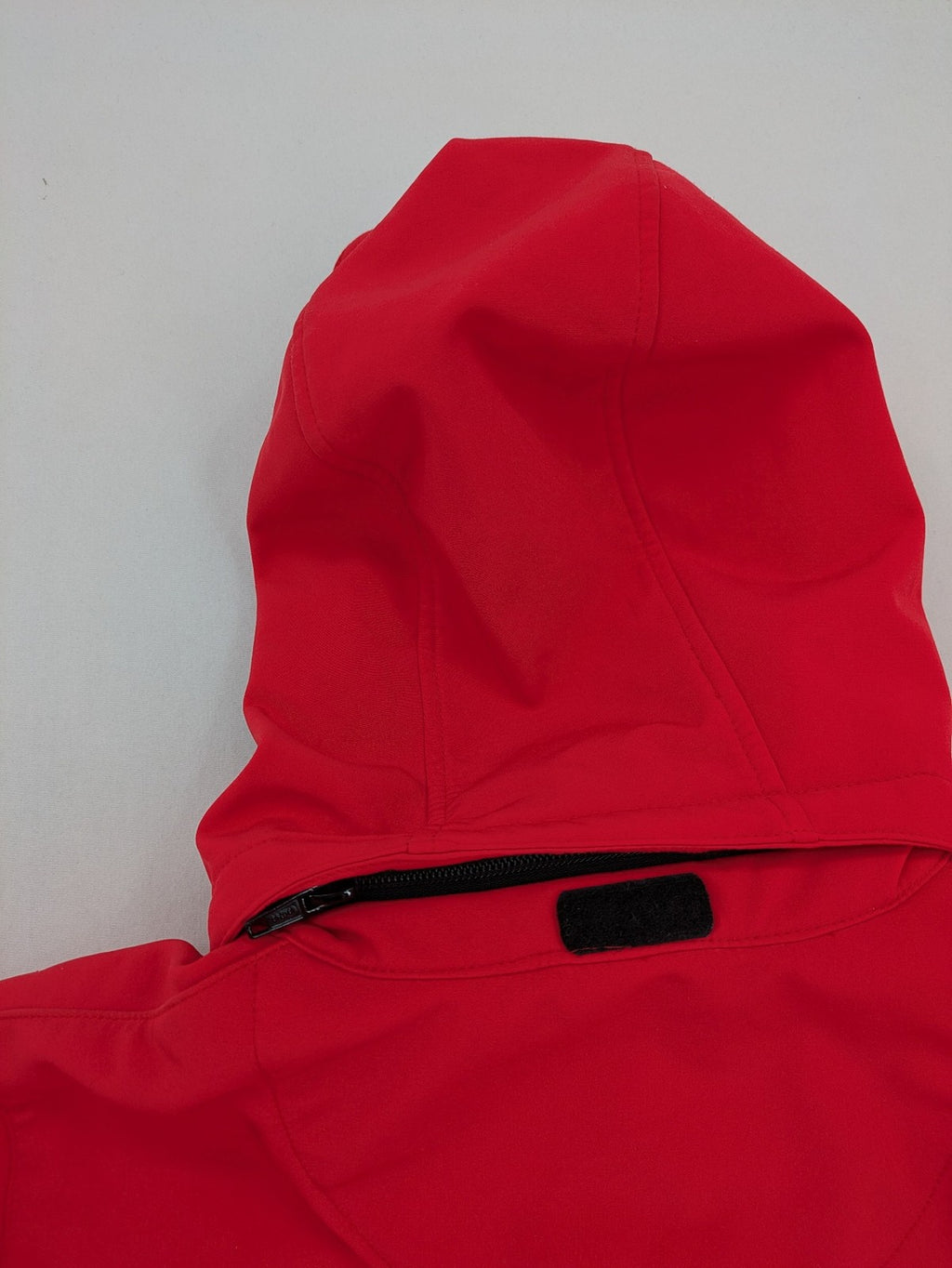 Pinea red softshell jacket with adjustable hood and fleece lining, multiple zippered pockets.