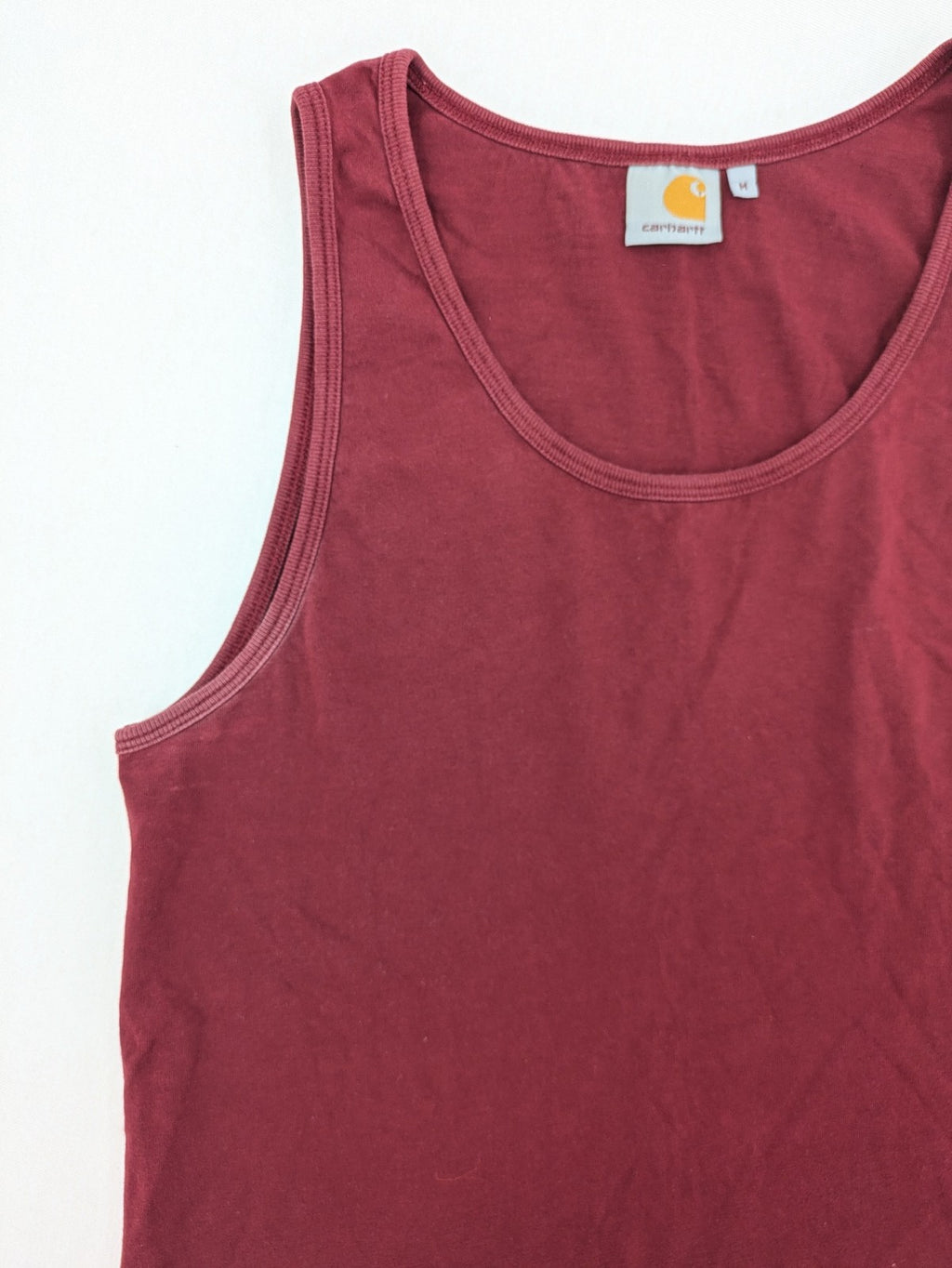Carhartt burgundy tank top 100% cotton with iconic logo patch at hem.