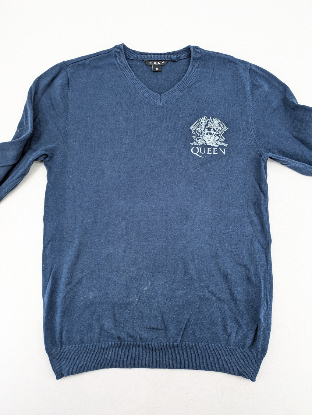 Queen blue knit jumper with embroidered crest logo, V-neck, 100% cotton.
