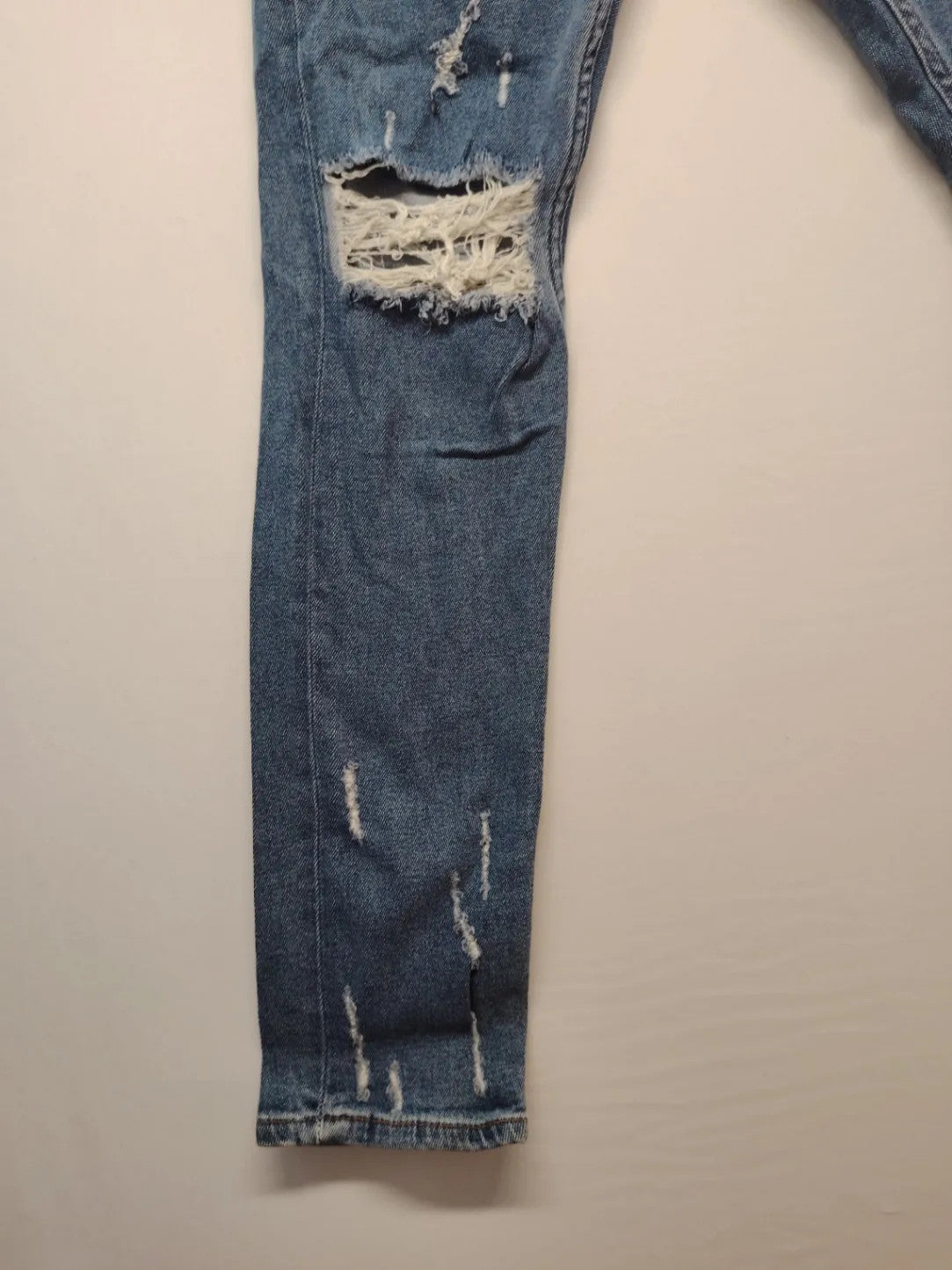 Damen blue skinny jeans with ripped details, five-pocket style, and classic button closure.