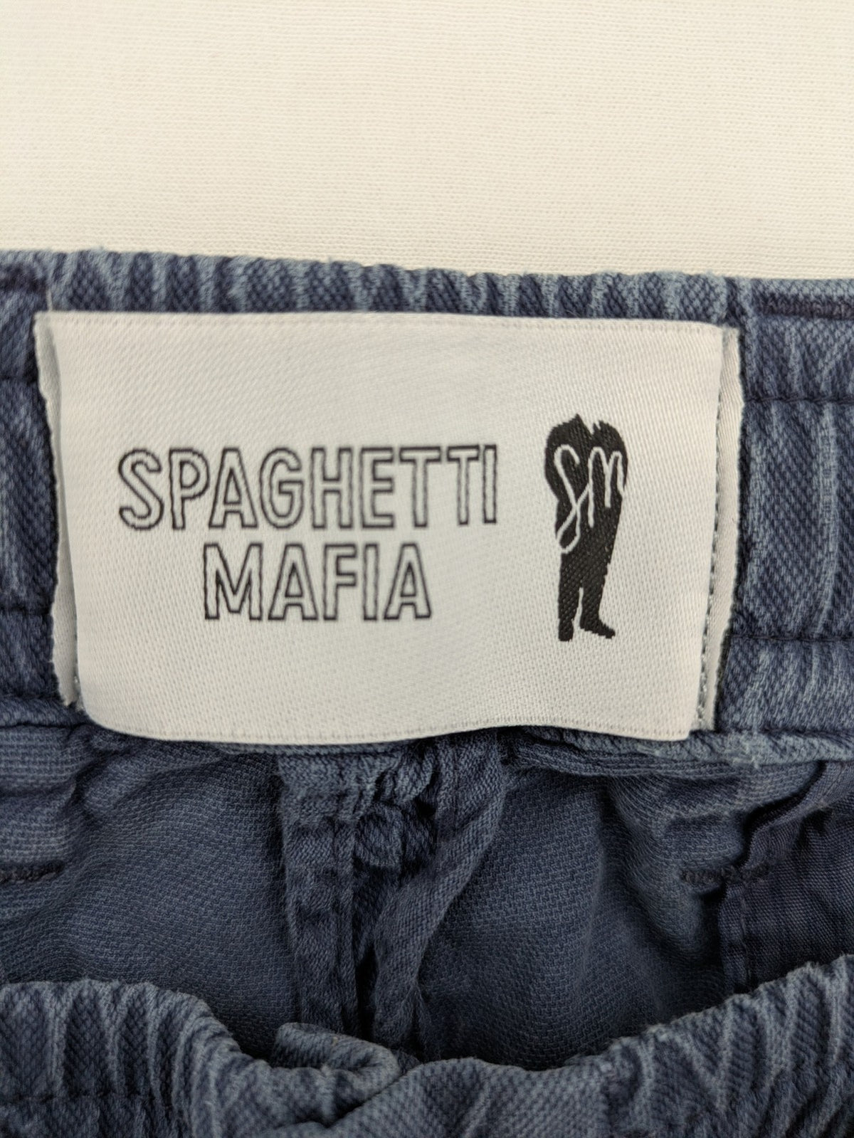 Spaghetti Mafia cream pants with elastic waistband, drawstring, and subtle front pleats.