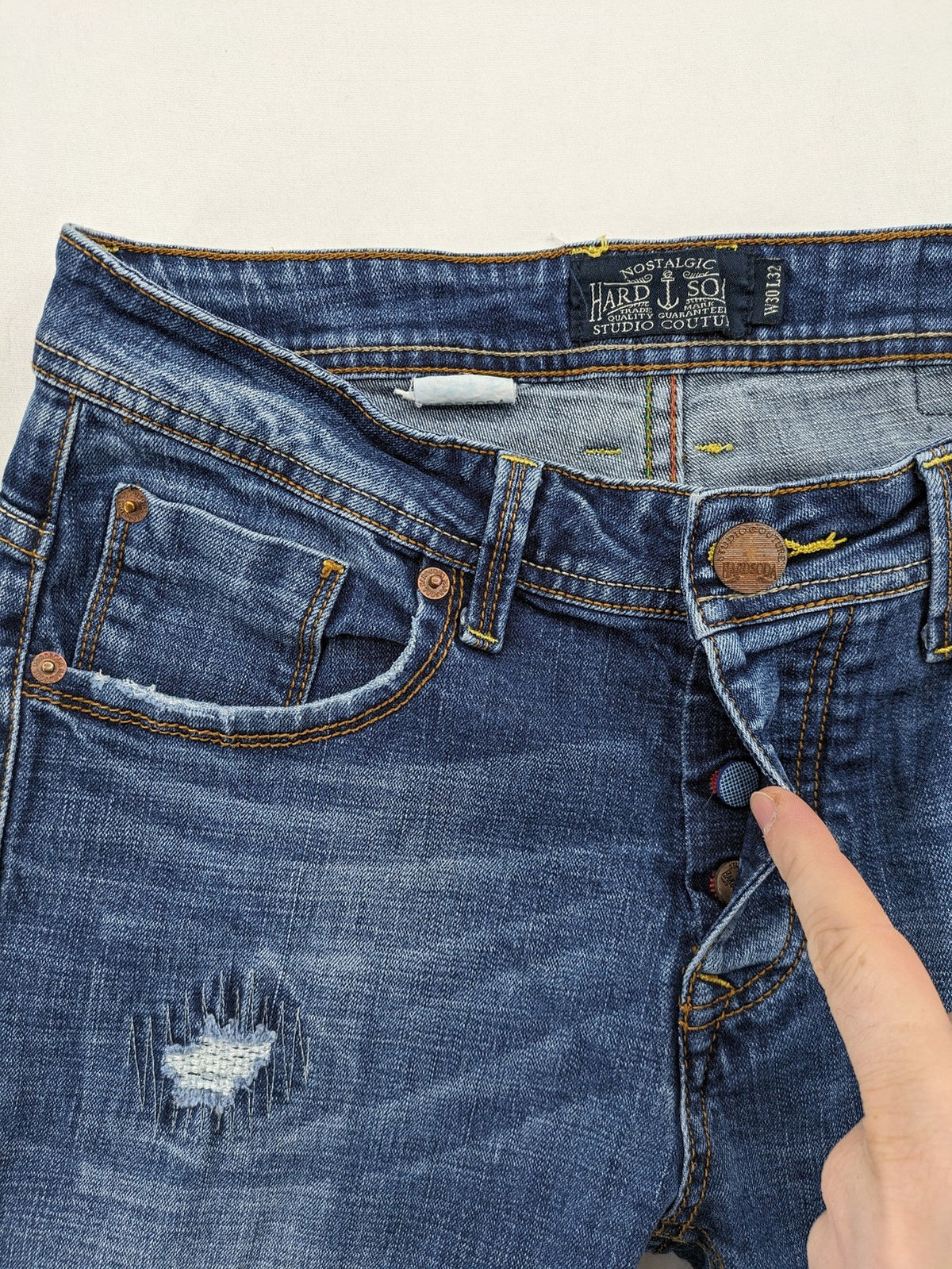 Soda blue straight jeans with distressed rips and button fly, cotton blend material.