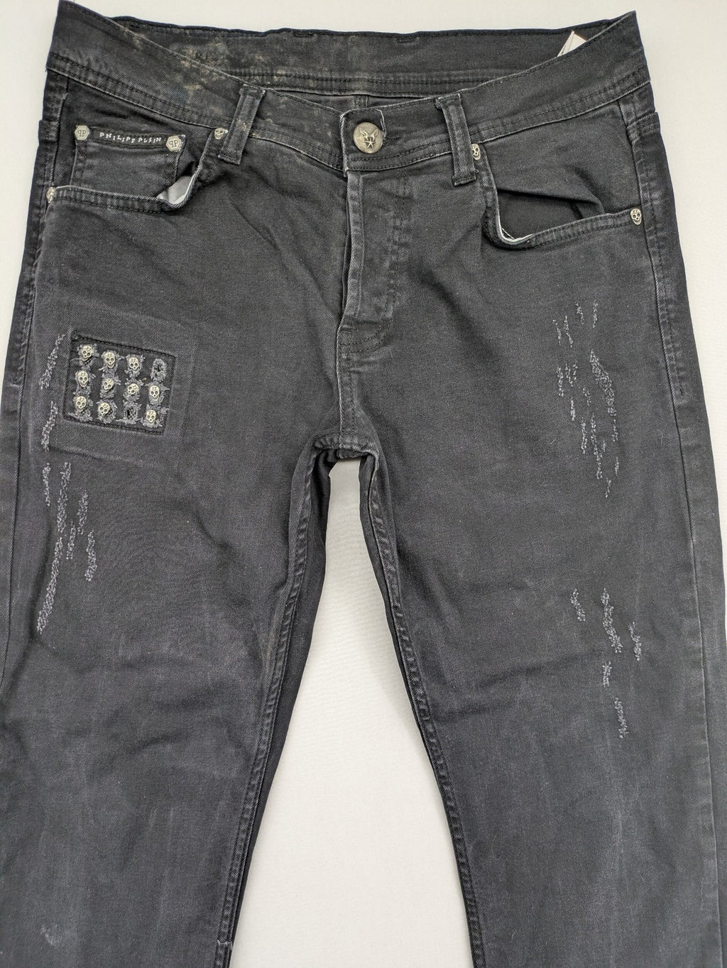 Philipp Plein black straight jeans with distressed finish and skull patch detail.