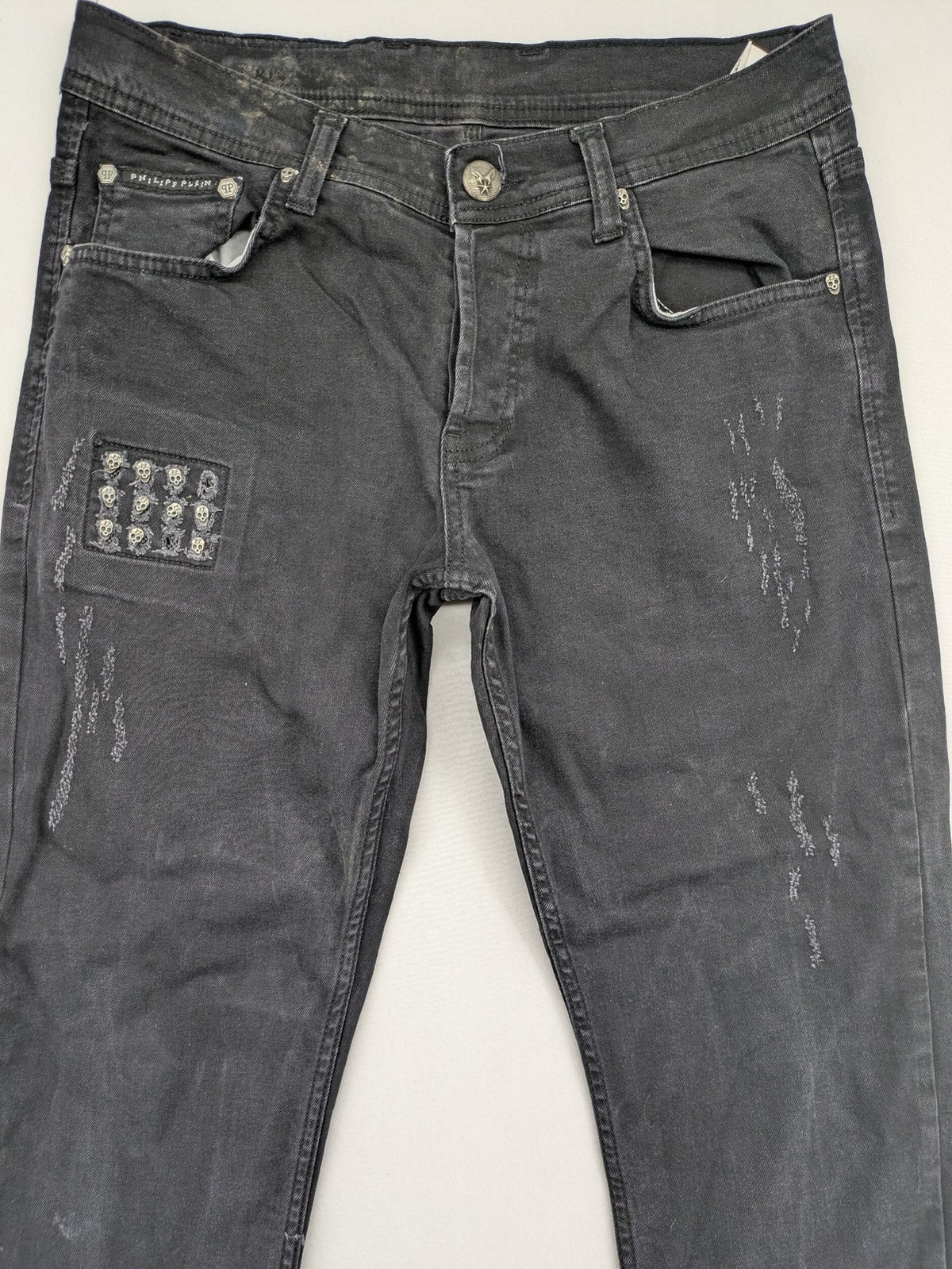 Philipp Plein black straight jeans with distressed finish and skull patch detail.