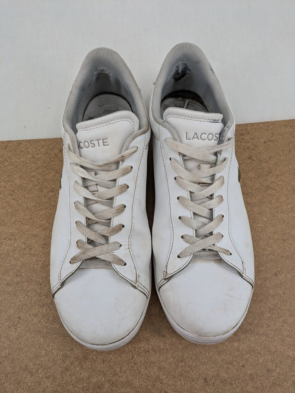 Lacoste cream low top sneakers with iconic crocodile logo and classic design.