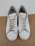Lacoste cream low top sneakers with iconic crocodile logo and classic design.