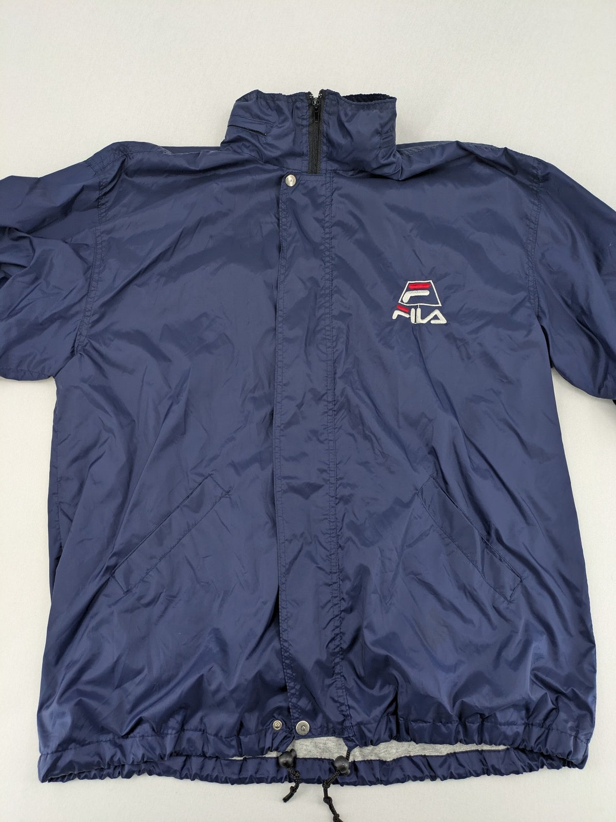 Fila navy windbreaker jacket with large embroidered logo on chest and back.