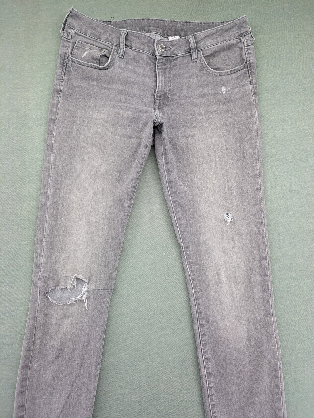 H&M grey super skinny jeans with distressed knee details and low waist fit.