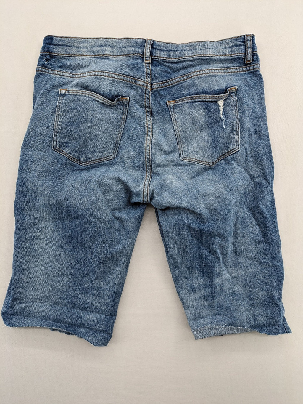 Denim blue distressed jeans shorts with frayed edges and a trendy used look.