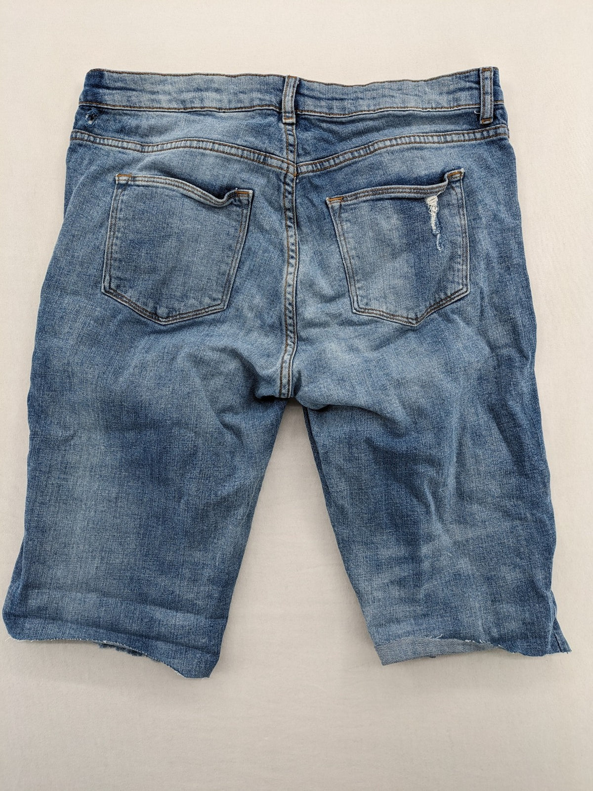 Denim blue distressed jeans shorts with frayed edges and a trendy used look.